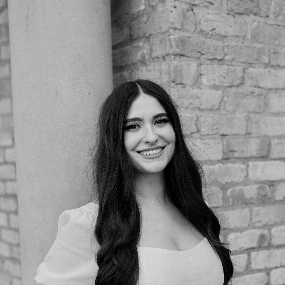 Black and white portrait of Jaden Wolfe smiling in front of a brick wall